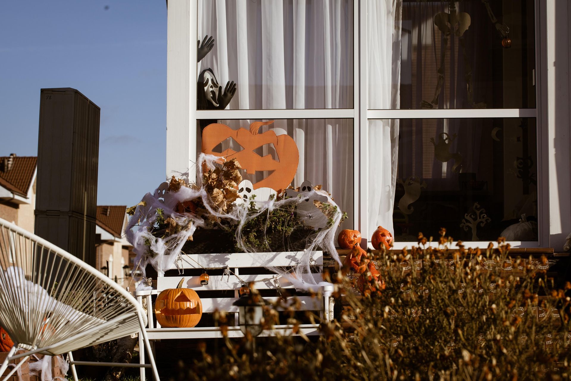 Front porch decorated for Halloween with pumpkins, cobwebs, and ghost figures.